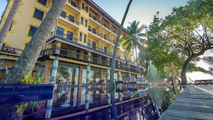 Un hotel de varios pisos con balcones, piscina y palmeras.