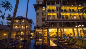 Un hotel de varios pisos con balcones, asientos al aire libre y una zona de piscina.