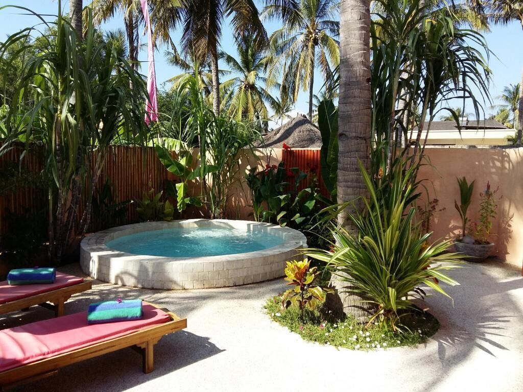 A hot tub surrounded by palm trees and lounge chairs.