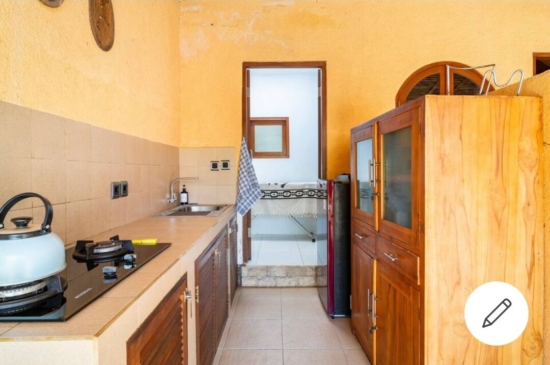 A compact kitchen with a gas stove, a sink, and wooden cabinets.