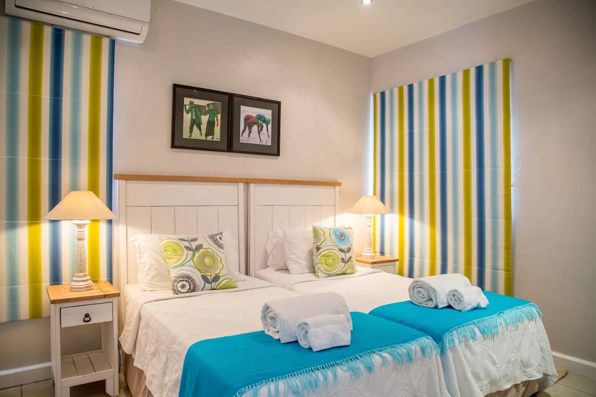 A double room with two beds, striped curtains, and a framed picture on the wall.