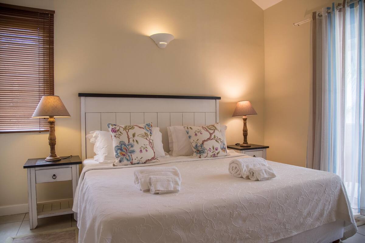 A neatly made bed with floral pillows, two bedside lamps, and a headboard.