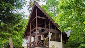 A cabin with a triangular roof, large windows, and a wooden deck.