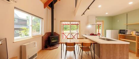 A modern kitchen with a central island, wooden flooring, and a large window.