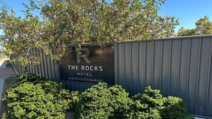 A sign for The Rocks Motel & Licensed Restaurant with a metal fence and green shrubs in front. - The Rocks Motel (Charleville)