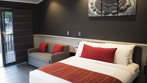 A modern hotel room with a large bed, a sofa, and a dining table. - The Rocks Motel (Charleville)