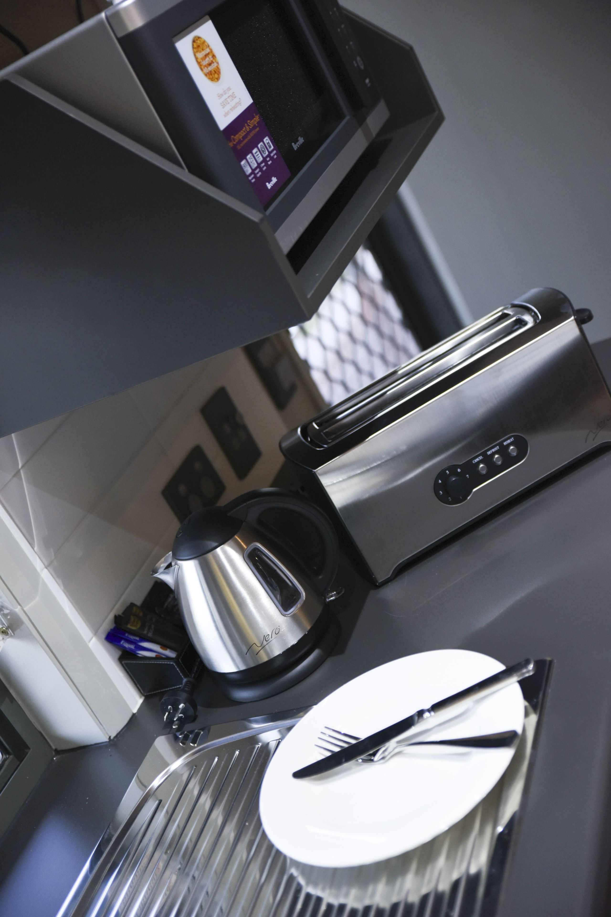 Una cocina con cafetera, tostadora y un plato con cubiertos.