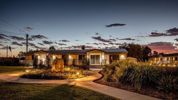 A two-story house with a covered porch, a large rock centerpiece, and a well-maintained lawn. - The Rocks Motel (Charleville)