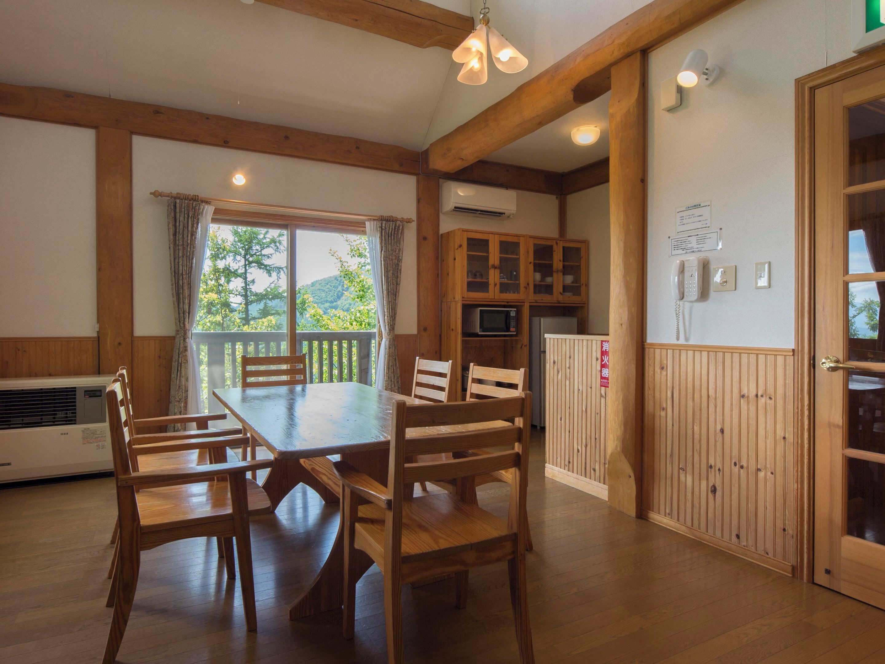 Une table à manger en bois avec des chaises, un coin cuisine avec des placards, un four à micro-ondes et un réfrigérateur.