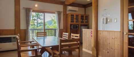 Une table à manger en bois avec des chaises, un coin cuisine avec des placards, un four à micro-ondes et un réfrigérateur.