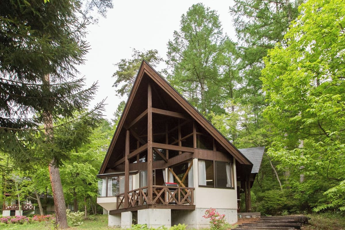 A cabin with a wooden structure, a balcony, and a staircase leading to the entrance.
