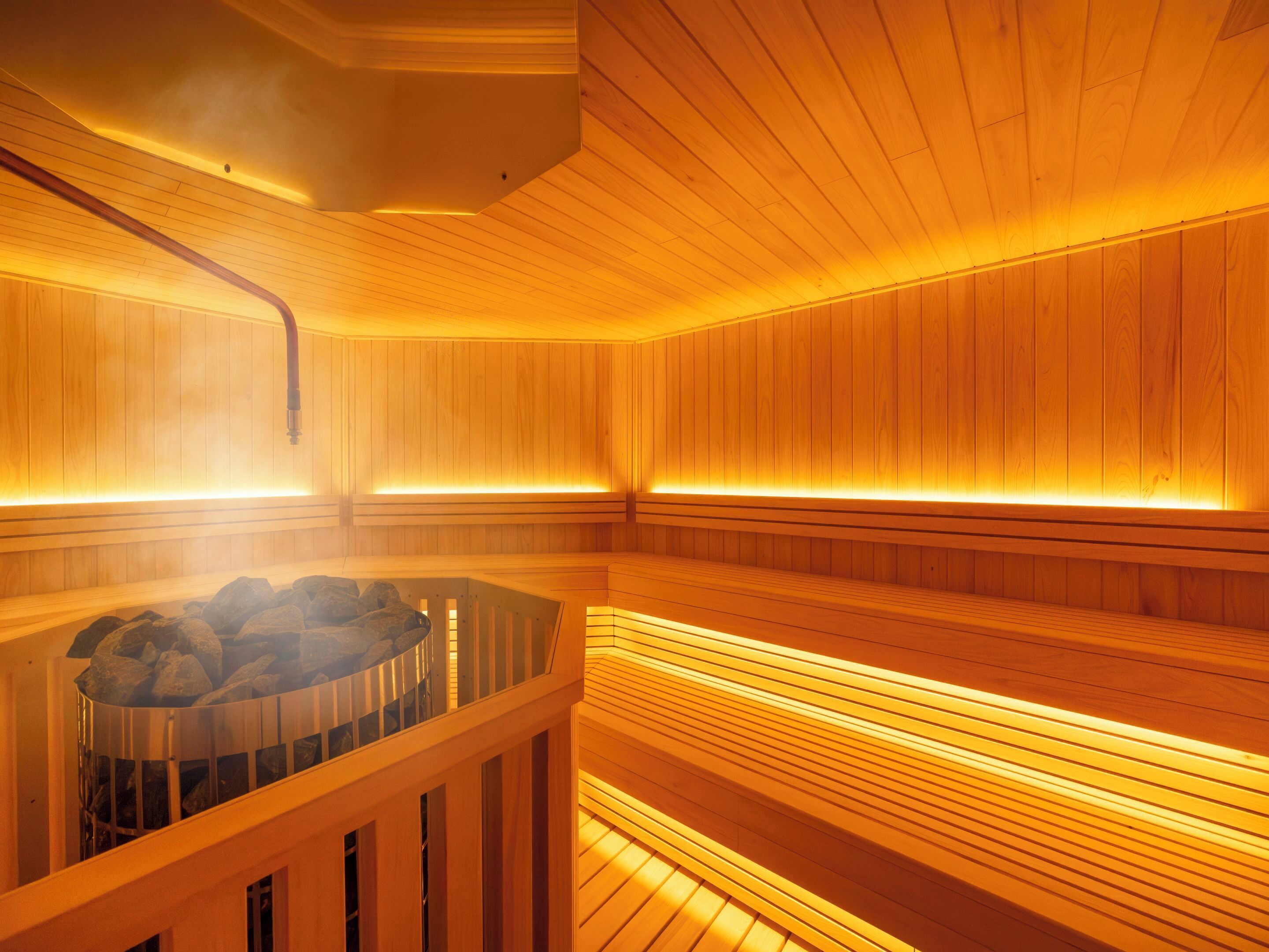 A sauna with wooden walls and benches, a steam room, and a visible heating system.