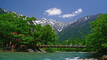 A wooden bridge over a river with a mountainous backdrop.