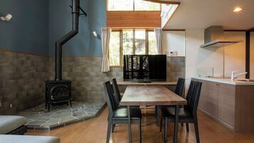 Una cocina moderna con estufa integrada, un comedor con mesa y sillas de madera, y un ventanal que proporciona luz natural.