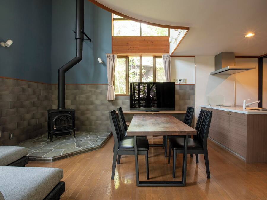 Una cocina moderna con estufa integrada, un comedor con mesa y sillas de madera, y un ventanal que proporciona luz natural.