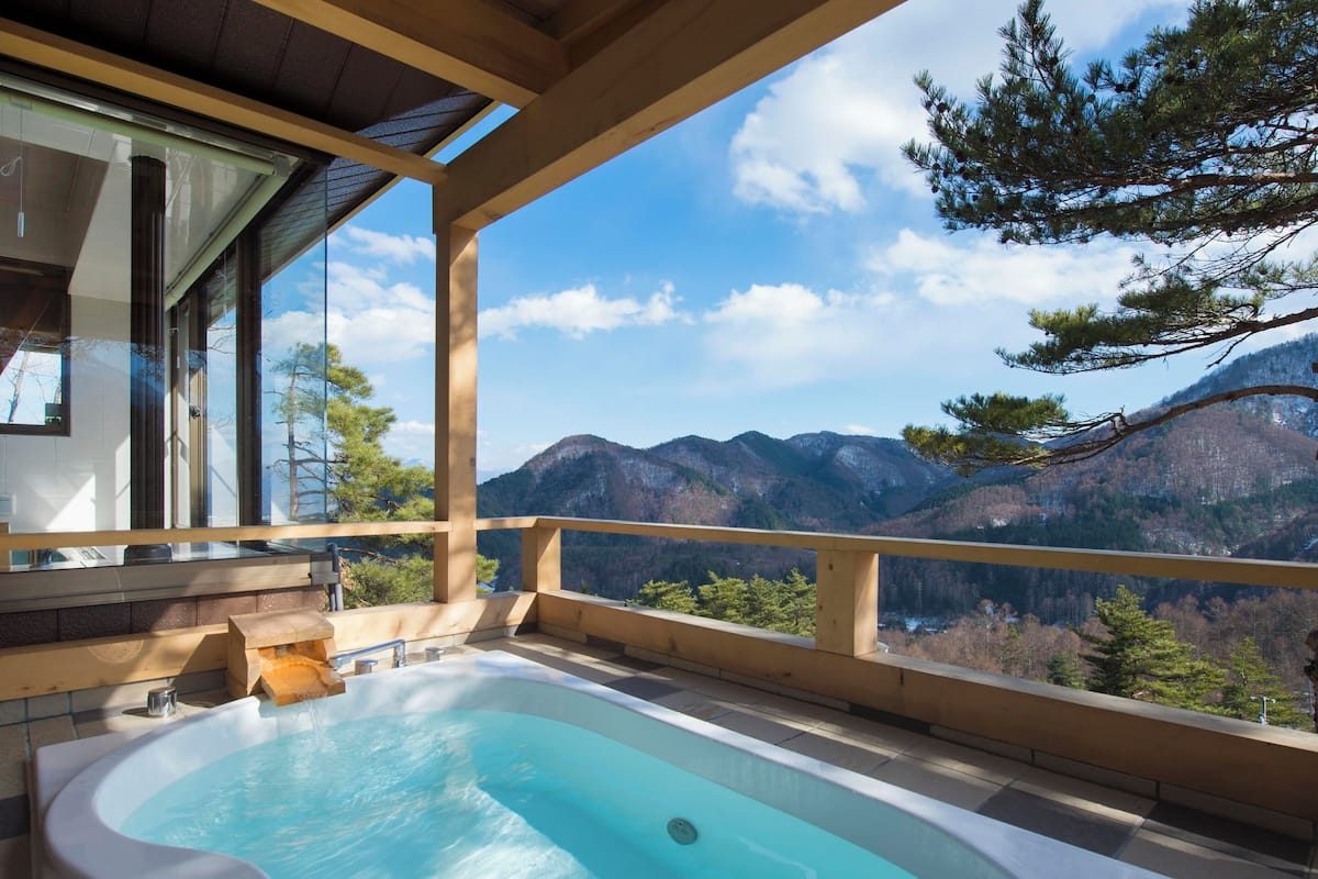 A balcony with a hot tub overlooking a mountainous landscape.
