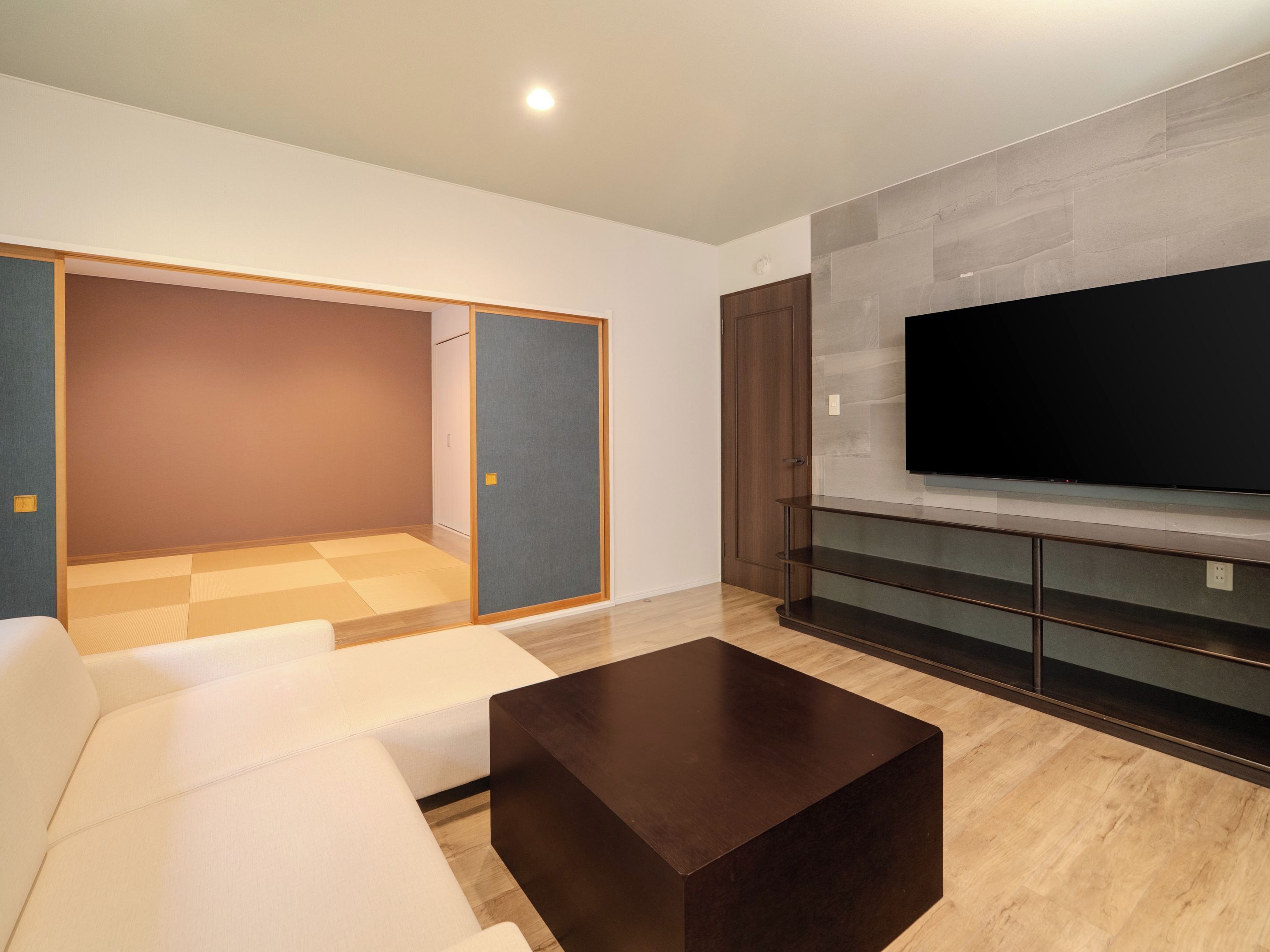 A modern living room with a sofa, a coffee table, a TV, and a sliding door.