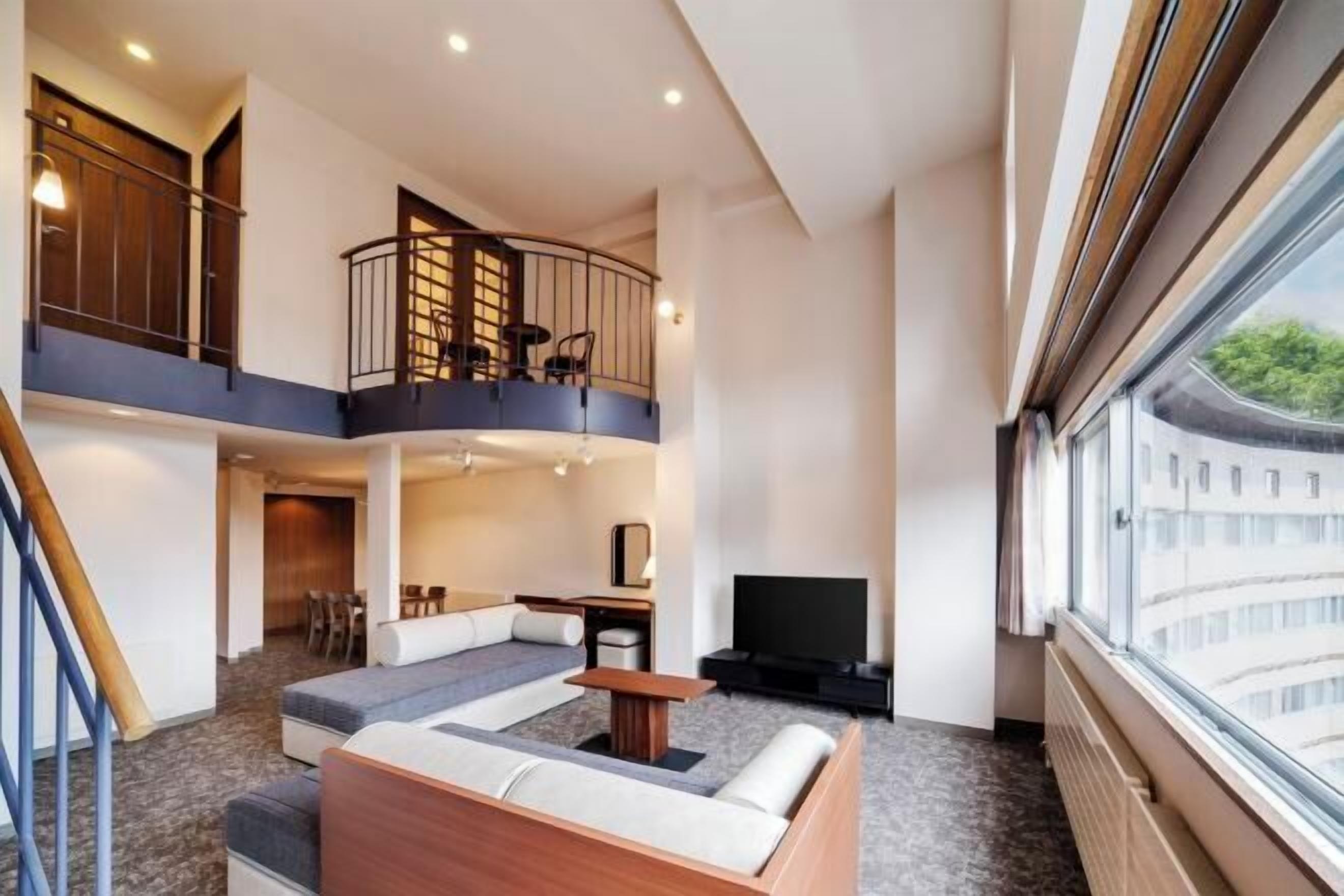 Un intérieur moderne comprenant un coin salon, un téléviseur et un balcon.