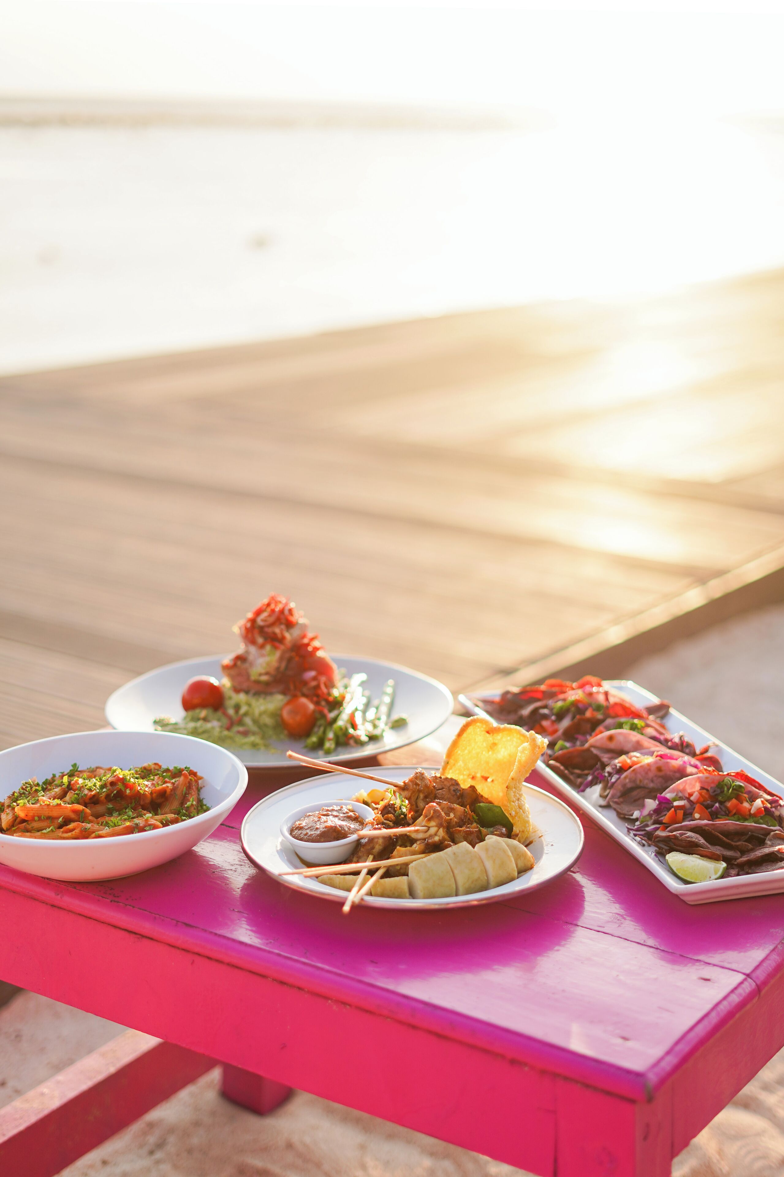 Una mesa con diversos platos en una terraza de madera.