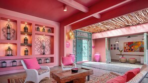 Un intérieur aux tons roses, avec des meubles en osier, un tapis à motifs et des lanternes décoratives.