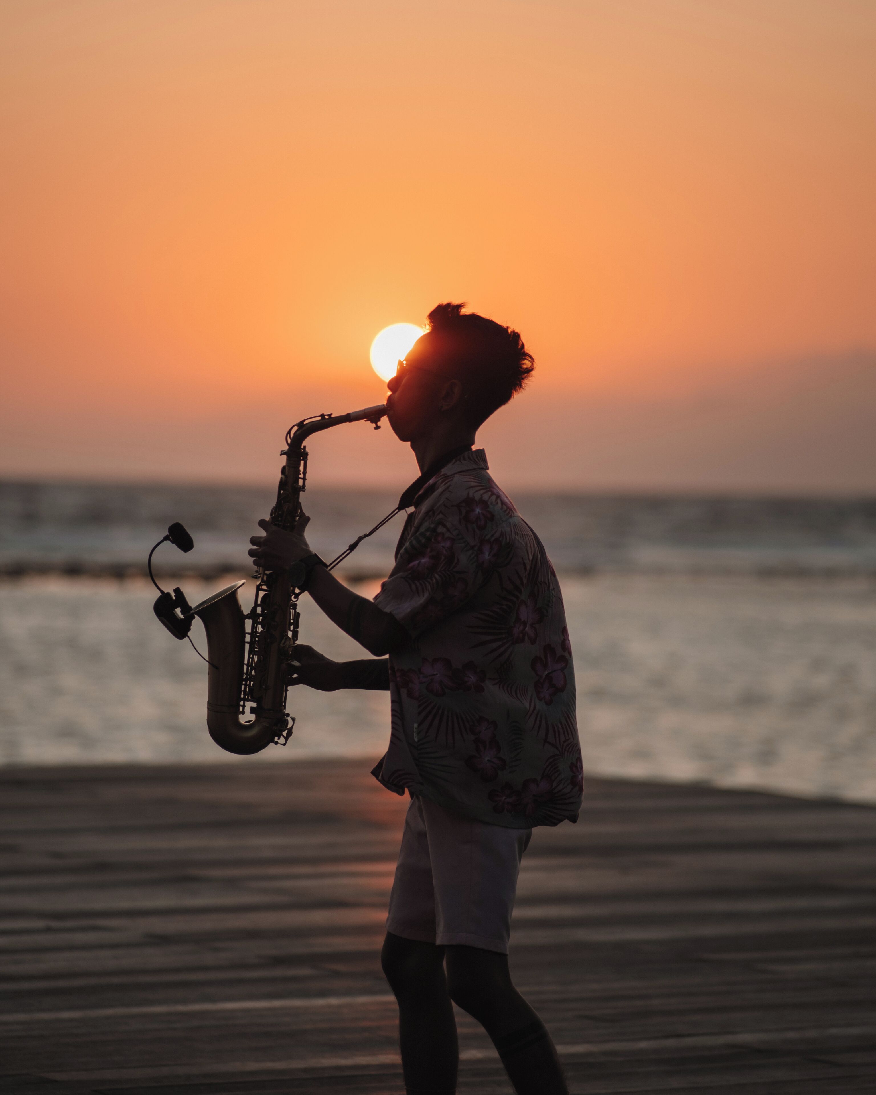 Una persona tocando el saxofón en la playa al atardecer.