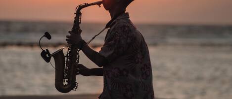 Una persona tocando el saxofón en la playa al atardecer.