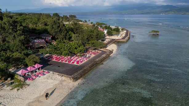 Une station balnéaire dotée d’une plage, d’une jetée et offrant une vue sur la mer et les montagnes.