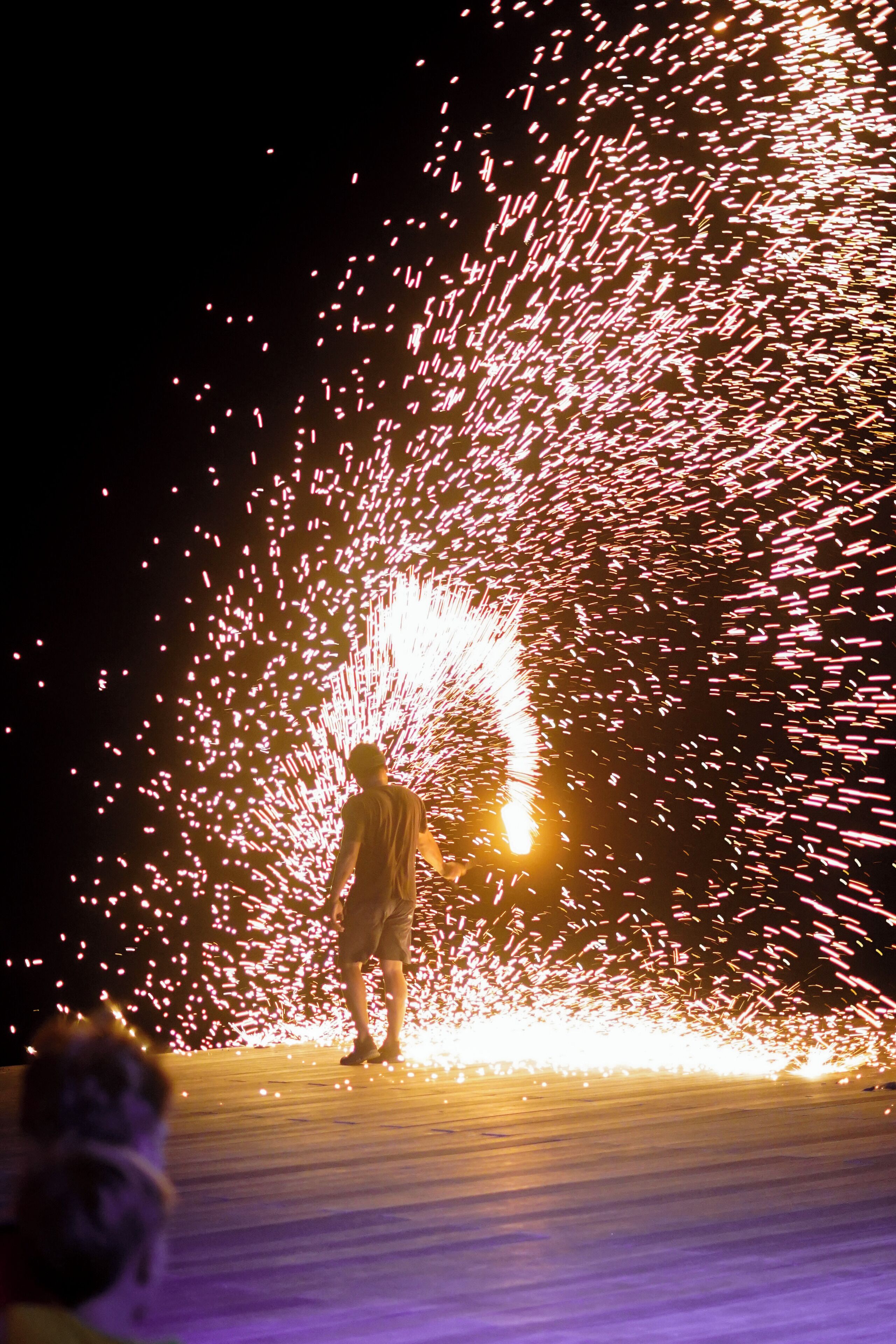 A person standing on a stage with a firework display.