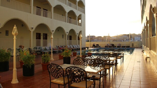 Eine Dachterrasse mit Sitzgelegenheiten im Freien, einem Pool und einem mehrstöckigen Gebäude mit Balkonen.
