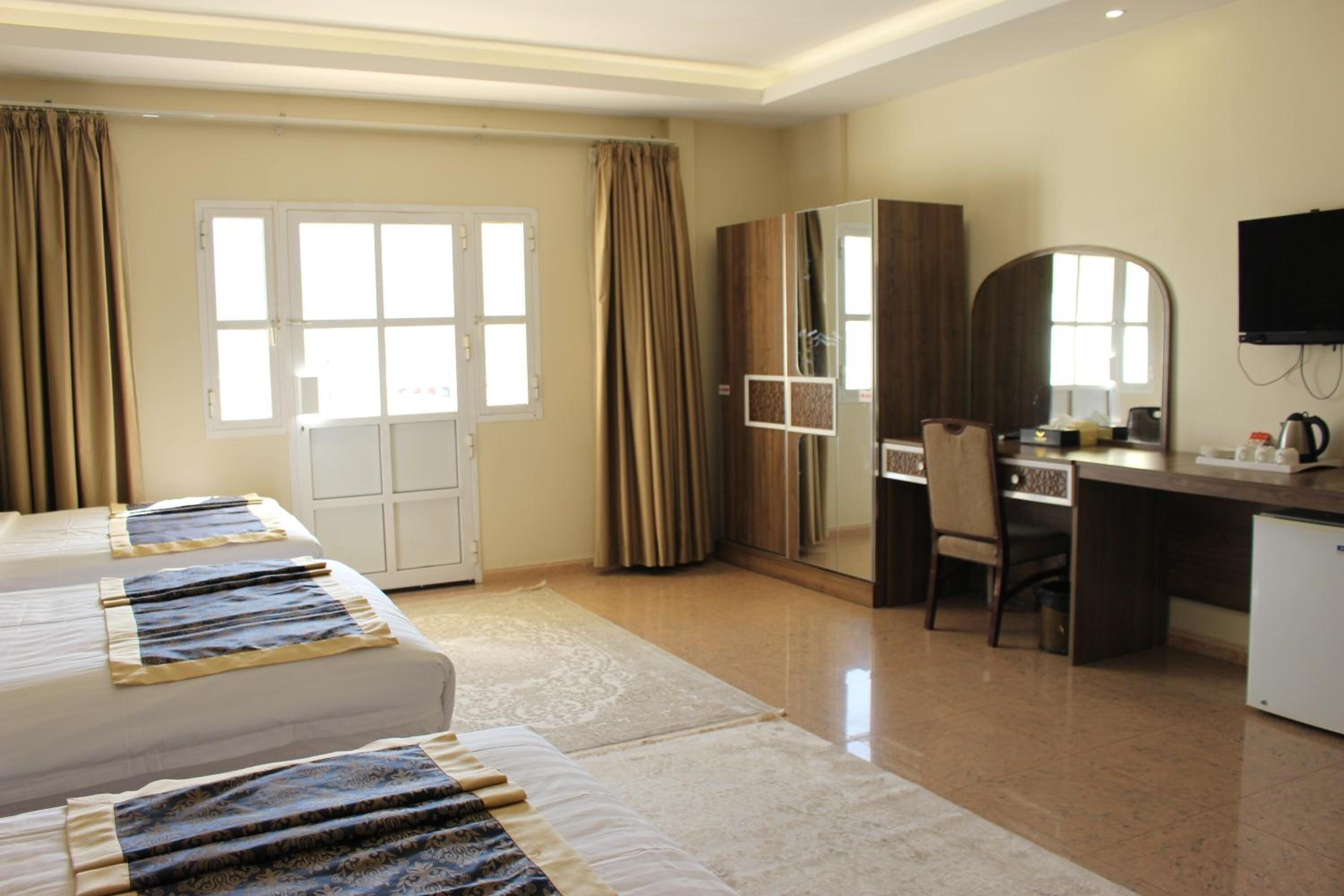 Une chambre d’hôtel comprenant un lit, un bureau, une chaise, une télévision et une armoire.