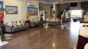 Eine geräumige Lobby mit einer imposanten Treppe, einer Sofagarnitur mit floralen Kissen und einer Kristallleuchter.