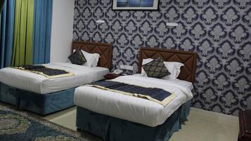 A hotel room with two beds, each with a headboard, a bedside table, and a telephone.