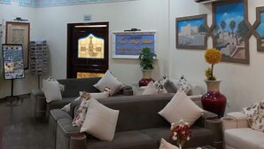 Eine Lobby mit grauem Sofa, roter Vase und Wandklimaanlage.