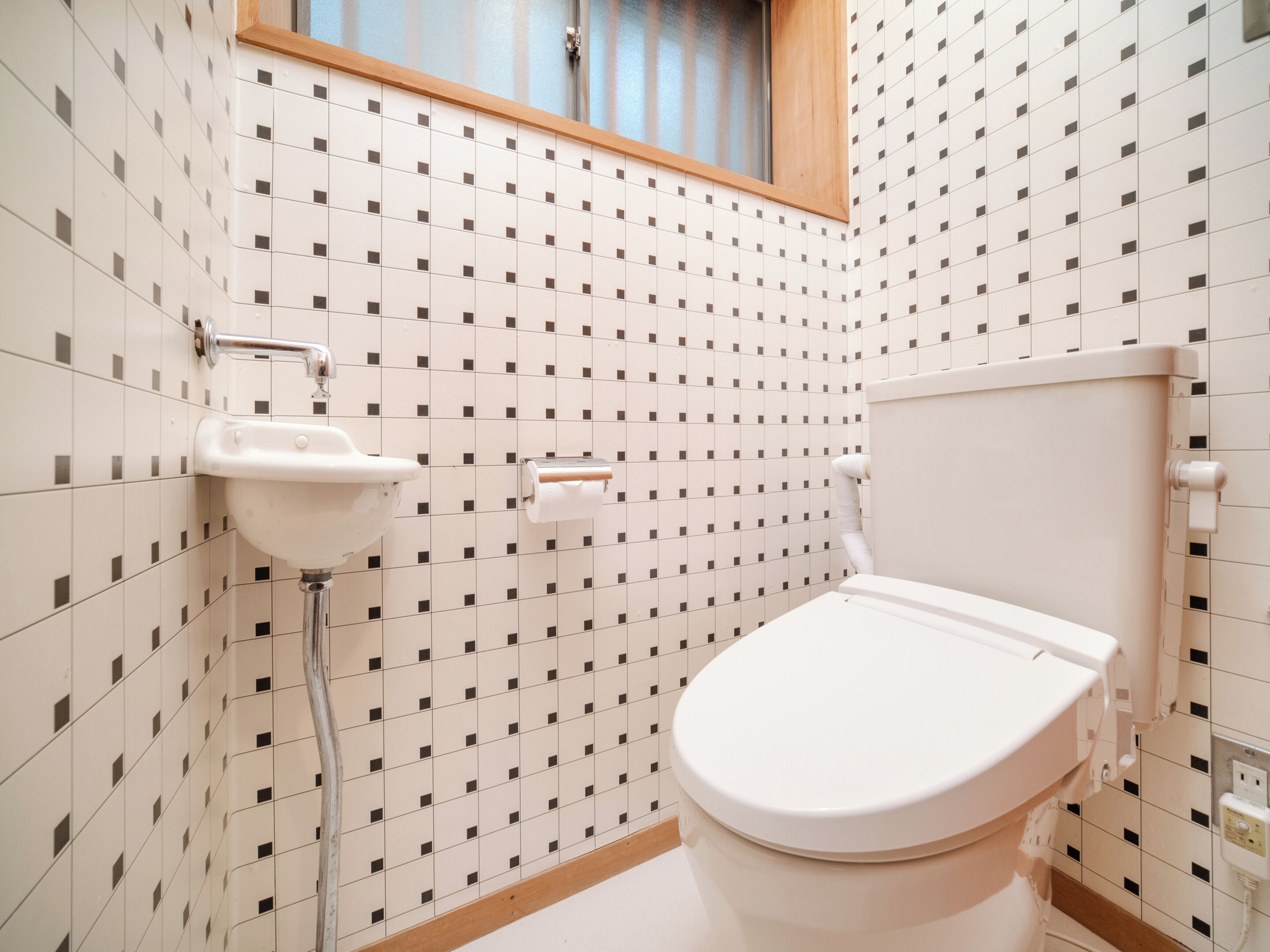 A bathroom with a toilet, sink, and window.