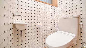 A bathroom with a toilet, sink, and window.