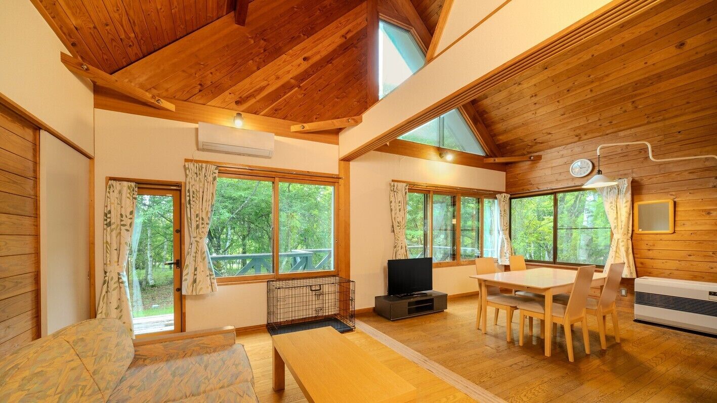 Un intérieur en bois comprenant une table à manger, des chaises, un téléviseur et de grandes fenêtres.