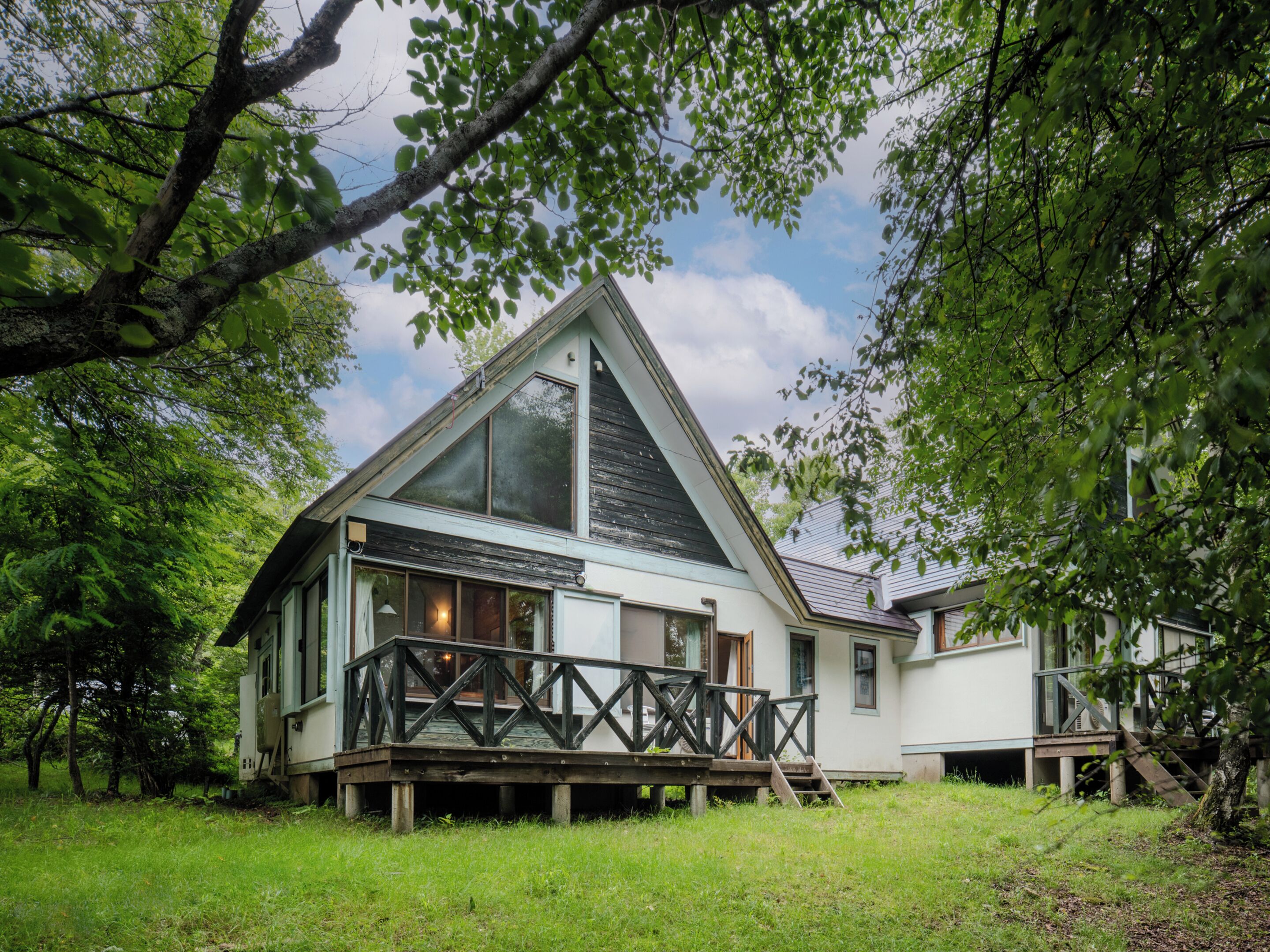A house with a large deck, a triangular roof, and a view of the sky.
