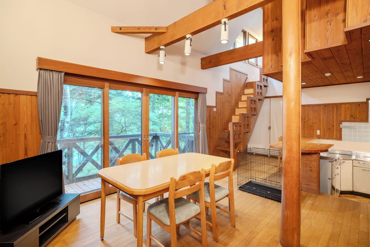 Un interior de madera con una mesa de comedor, sillas, un televisor y una escalera.