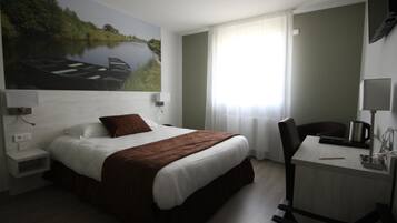 Una camera d'albergo con un letto, una scrivania, una sedia, una televisione e un quadro raffigurante un paesaggio fluviale.