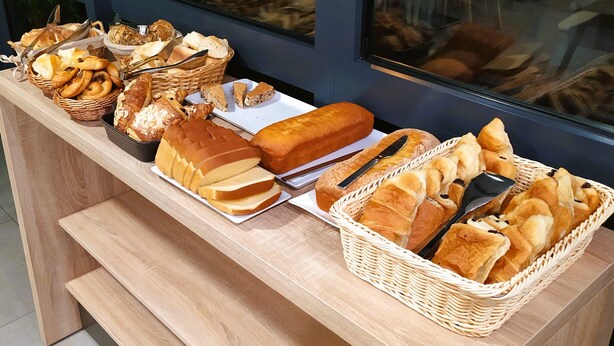 Una mesa de buffet con panes y pasteles varios.