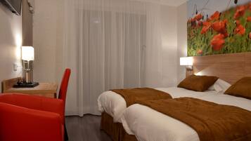 Une chambre d’hôtel avec un lit, deux tables de chevet avec des lampes, un fauteuil rouge et une fresque murale représentant des coquelicots.