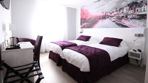 Habitación de hotel con dos camas, un escritorio y una silla.