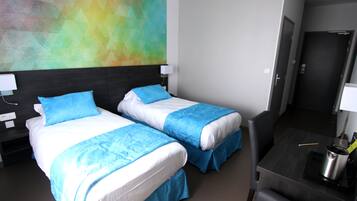 Ett hotellrum med två sängar, ett skrivbord och en färgstark, abstrakt målning på väggen.
