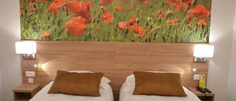 Habitación de hotel con dos camas, cabecero de madera, lámparas de noche y un cuadro mural de una gran amapola.