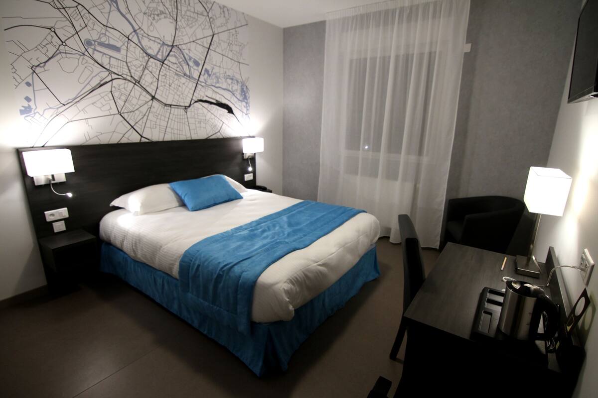 Una habitación de hotel con una cama, un escritorio, una silla y un mapa en la pared.