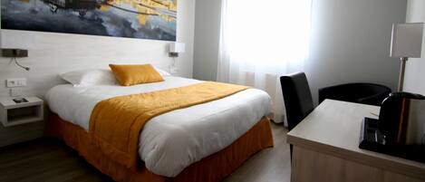 Una habitación de hotel con una cama grande, un escritorio, una silla y un cuadro en la pared.