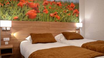 A hotel room with a large poppy field mural, a wooden headboard, two beds with brown bedding, and bedside lamps.