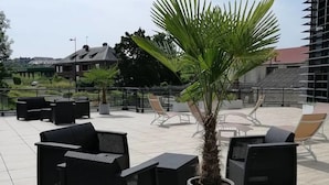 Un patio en la azotea con mobiliario exterior y una palmera.