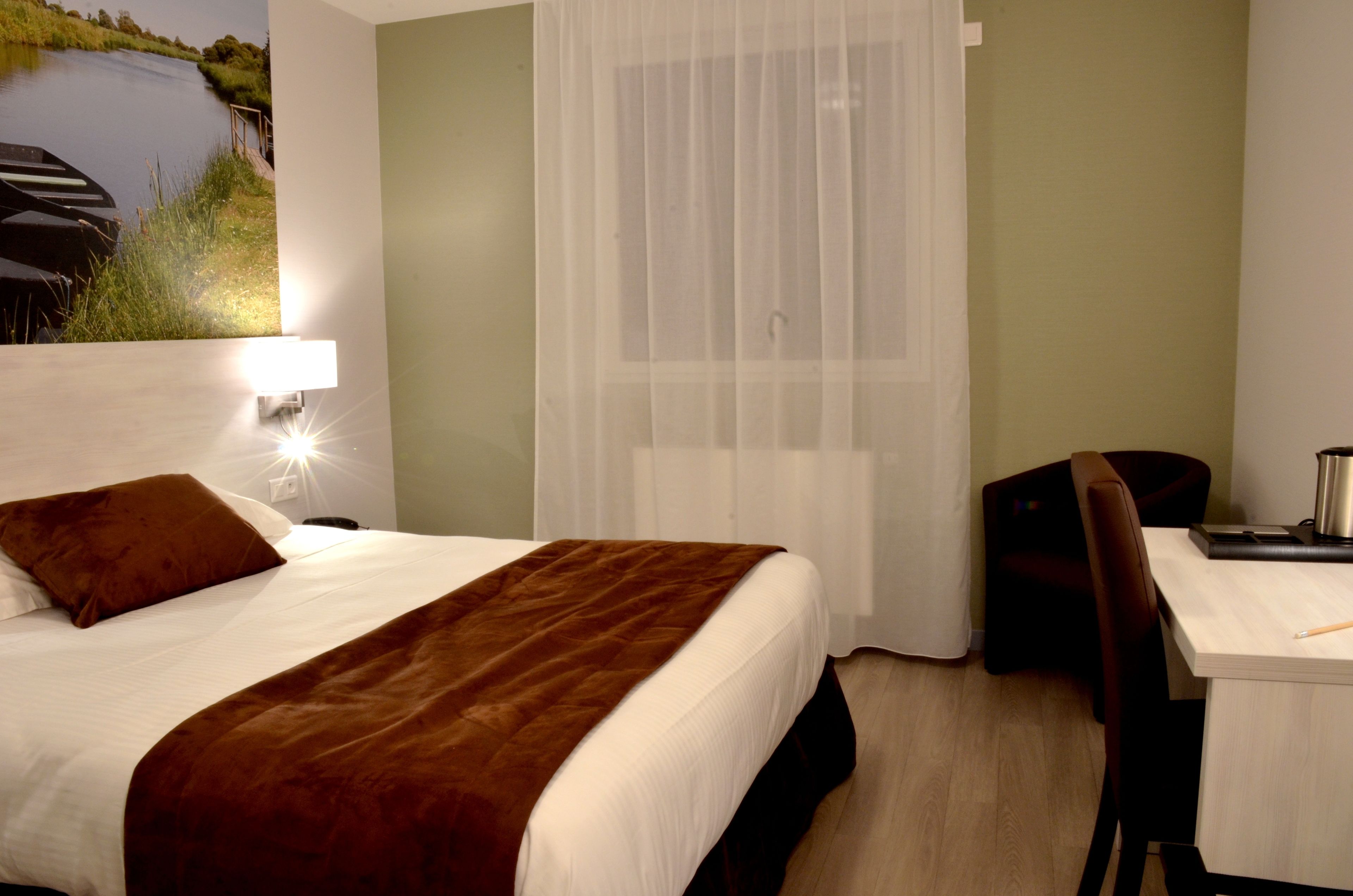 Habitación de hotel con cama, escritorio y vista a un cuerpo de agua.