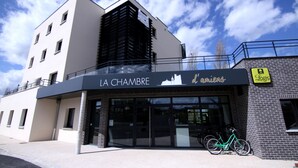Un edificio moderno con un letrero que dice "LA CHAMBRE d'ambiens" y una bicicleta estacionada afuera.